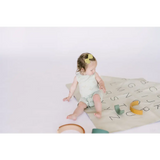 Baby enjoying the Hummingbird Pocket Playsuit on a colorful alphabet play mat