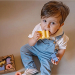 Young child in denim overalls enjoying bread with Floating Stacking Blocks in Natural Rubber