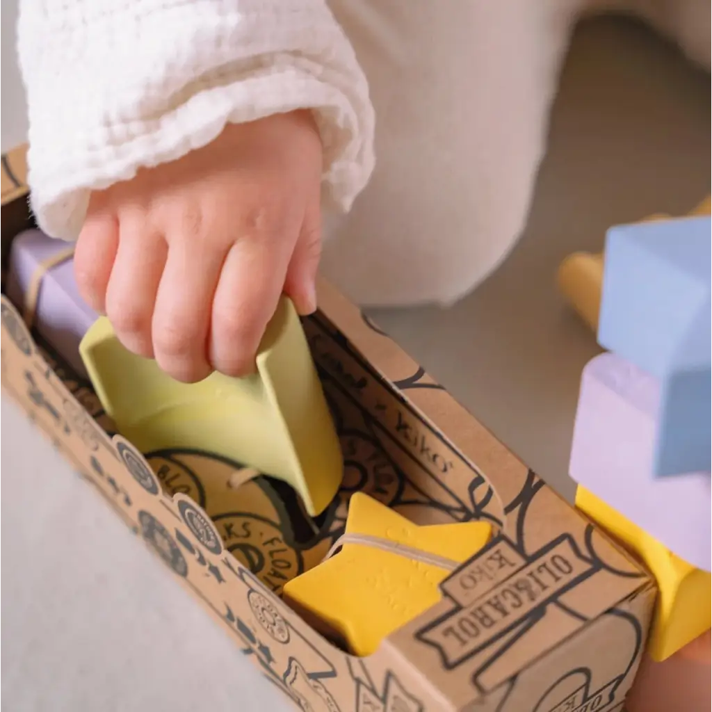 Small hand reaching for a yellow block in the Floating Stacking Blocks Set with geometric figures