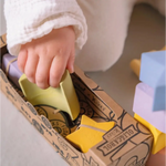 Small hand reaching for a yellow block in the Floating Stacking Blocks Set with geometric figures
