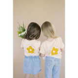 Two kids in matching Let Love Grow graphic t-shirts and denim outfits