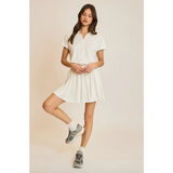Woman in a white polo shirt and skirt modeling the Libby Athletic Mesh Romper with Front Zip