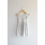 Light gray Libby Twirl Dress with daisy print hanging on a wooden hanger