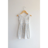Light gray Libby Twirl Dress with daisy print hanging on a wooden hanger