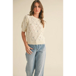 Woman wearing Liv Pointelle Knit Sweater with floral embroidery and light blue jeans