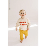 Toddler in cream Love is Rad baby pullover sweatshirt made from organic cotton fabric