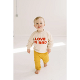 Toddler in cream Love is Rad baby pullover sweatshirt made from organic cotton fabric