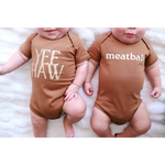 Two brown organic cotton baby onesies with polished prints YEE HAW and meatball designs