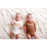 Two babies in coordinating organic cotton food-themed onesies, looking adorable together
