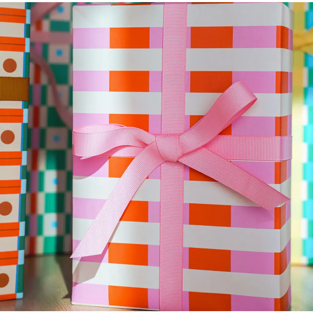 Gift-wrapped package in orange and white striped Merengue wrapping paper with pink bow