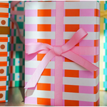 Gift-wrapped package in orange and white striped Merengue wrapping paper with pink bow