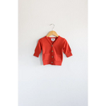 Buttery soft red mini grandpa cardigan sweater on a wooden hanger for the holiday season