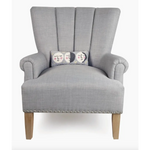 Gray upholstered armchair showcasing a hooked accent pillow with velvet backing