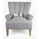 Gray upholstered armchair showcasing a hooked accent pillow with velvet backing