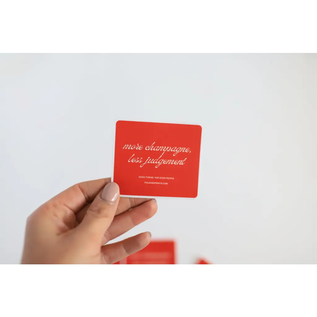 Hand holding a red Judgement waterproof sticker for playful vibes at parties