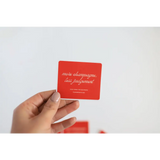 Hand holding a red Judgement waterproof sticker for playful vibes at parties