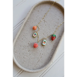 Gold chain necklace with colorful fruit-themed clay charms on a seaside charm necklace