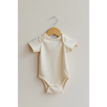 Cream-colored organic cotton baby bodysuit on a wooden hanger for your little one