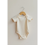 Cream-colored organic cotton baby bodysuit on a wooden hanger for your little one