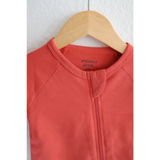 Coral Organic Cotton Baby Zipper Sleeper hanging on a wooden hanger for cozy comfort