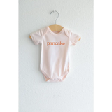 Light Pink Pancake Organic Cotton Onesie featuring orange pancake text for cozy cuties