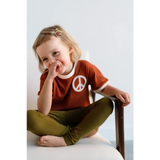 Giggling kid in rust Peace Embroidered Ringer Tee and olive pants, perfect for everyday fun