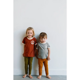 Two kids rocking peace embroidered ringer tees and colorful pants, barefoot and happy