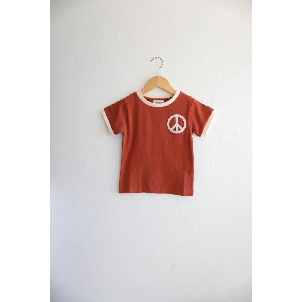 Rust Peace Embroidered Ringer Tee for Kids hanging on a hanger, perfect everyday ringer