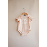 Pale pink Peace Floral Organic Cotton Baby Onesie hanging on wooden hanger
