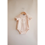 Pale pink Peace Floral Organic Cotton Baby Onesie hanging on wooden hanger