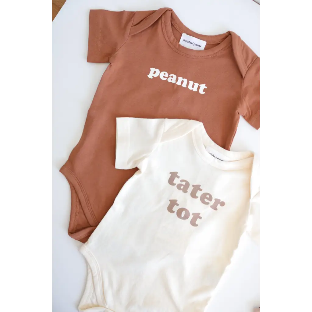 Two cute baby onesies in brown and cream saying Peanut and Tater Tot, made from organic cotton