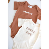Two cute baby onesies in brown and cream saying Peanut and Tater Tot, made from organic cotton