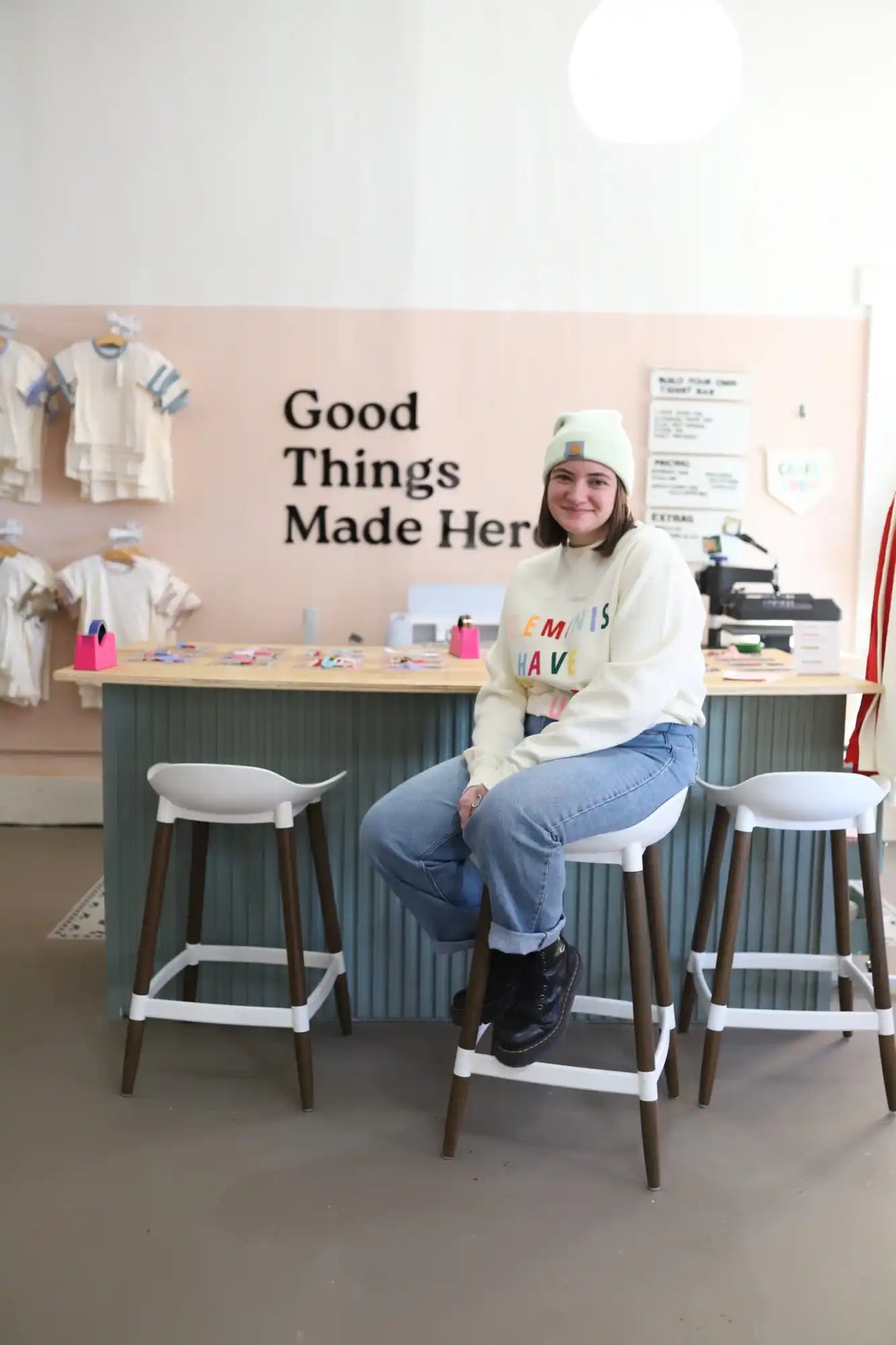 A person sitting on a barstool in a craft workshop space.