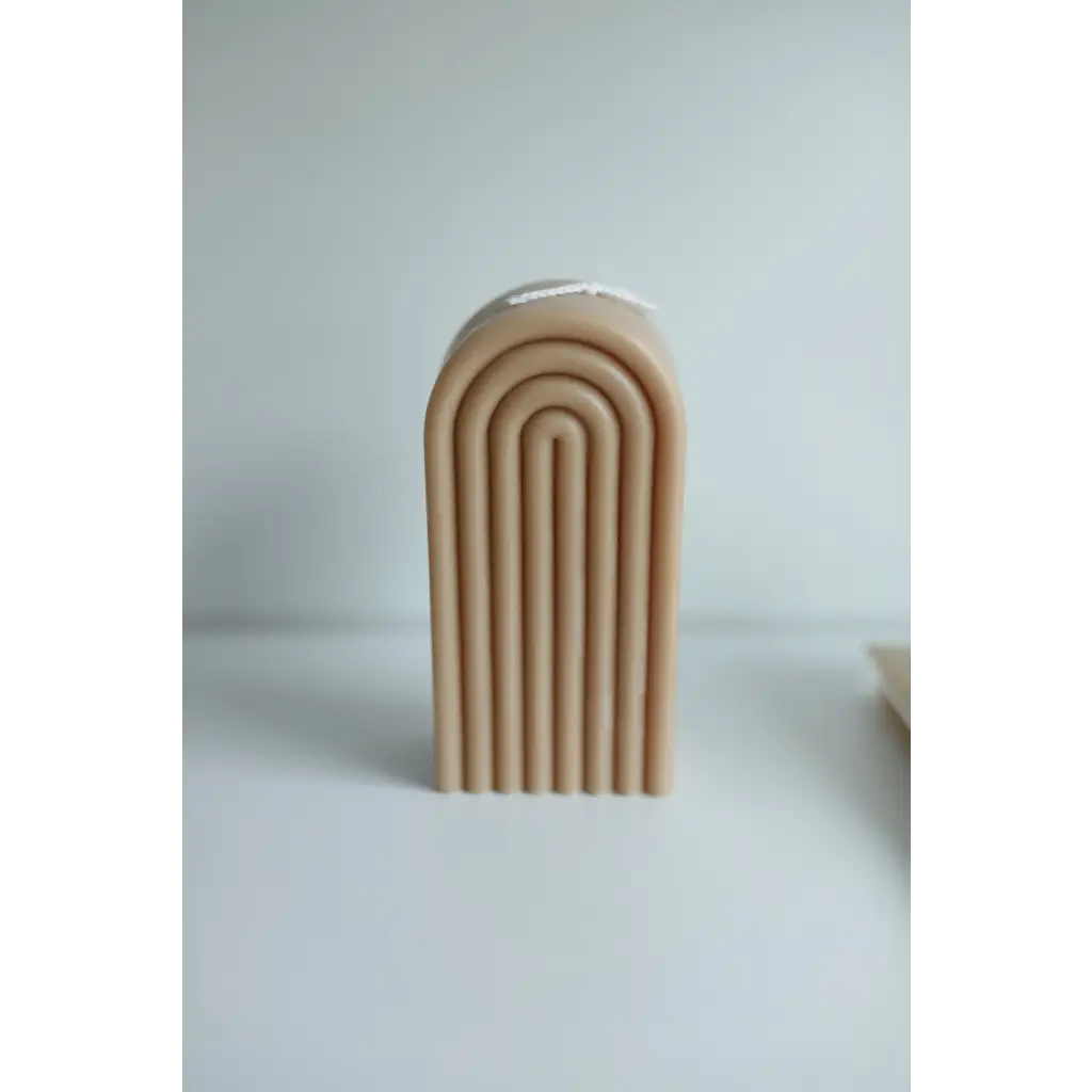 Cream-colored arch sculpture with curved lines around a Petite Rainbow Candle display