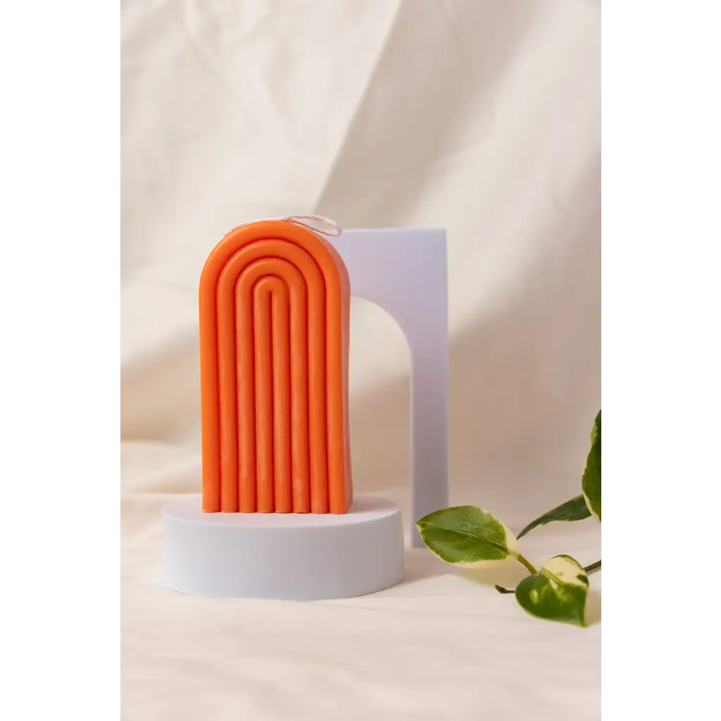 Cheerful orange silicone Petite Rainbow Candle with fun curved ridges on a white base