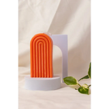 Cheerful orange silicone Petite Rainbow Candle with fun curved ridges on a white base