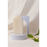 White ribbed arch-shaped Petite Rainbow Candle on a circular base for colorful decor