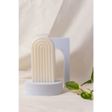 White ribbed arch-shaped Petite Rainbow Candle on a circular base for colorful decor