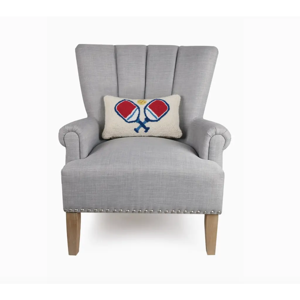 Gray armchair with wooden legs showcasing two crossed paddles throw pillow