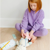 Child in a purple sweatsuit enjoying pretend play with plush bunny and Mint Green Felt Bandages