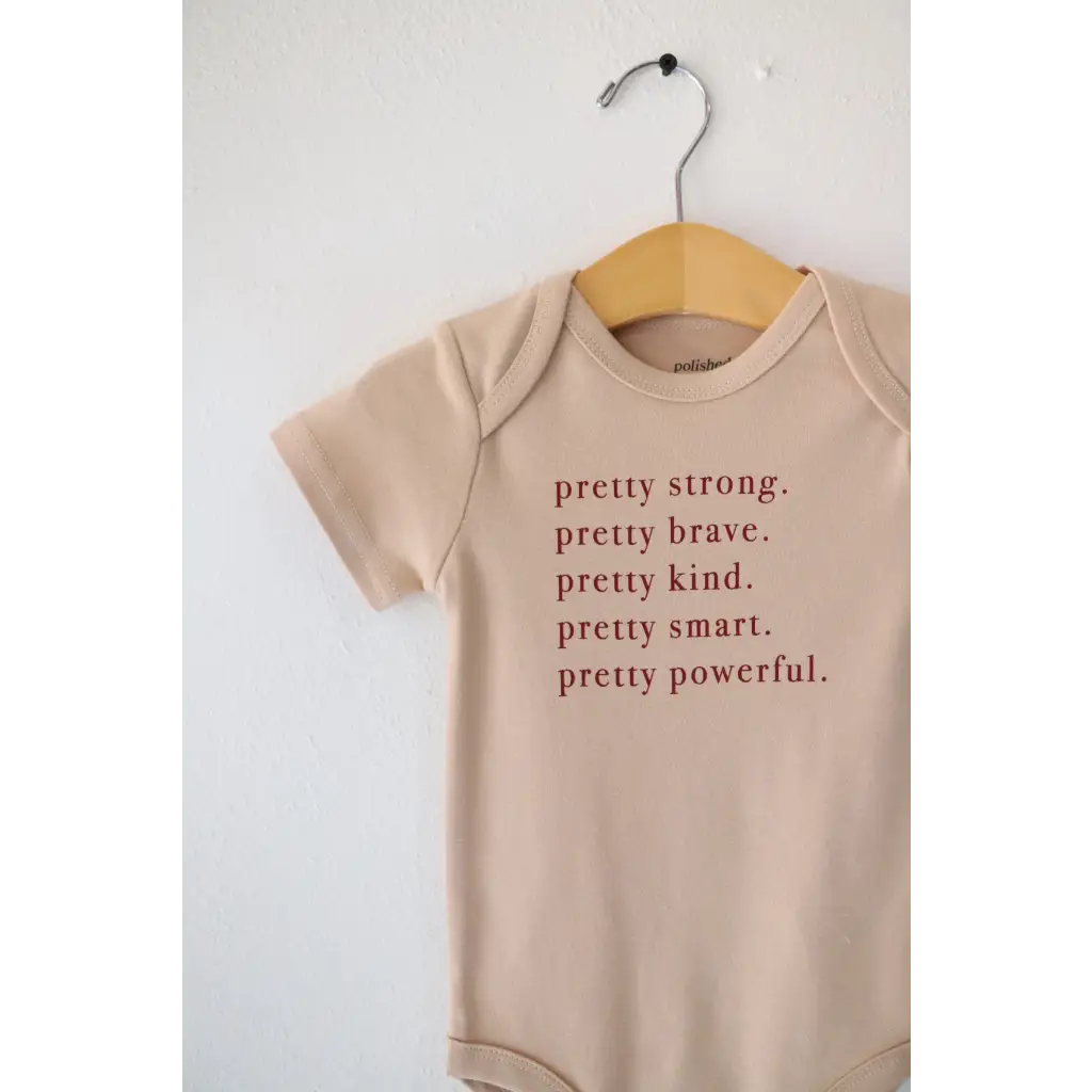 Tan baby onesie with empowering text made from pretty brave organic cotton