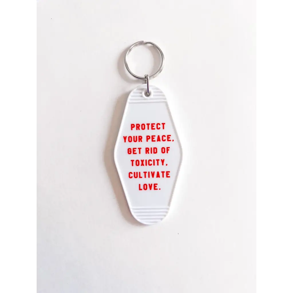 White acrylic retro motel keychain with red text promoting positivity and self-care