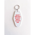 White acrylic retro motel keychain with red text promoting positivity and self-care