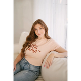 Person lounging in a Raise them Kind organic cotton graphic t-shirt and blue jeans