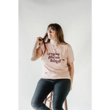 Pink graphic t-shirt with Raise Them Kind text, made from soft organic cotton
