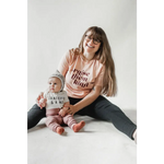 Parent and baby in matching Raise Them Kind organic cotton graphic t-shirts, cozy together