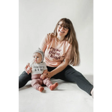 Parent and baby in matching Raise Them Kind organic cotton graphic t-shirts, cozy together