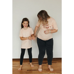Two people in matching peach organic cotton graphic t-shirts, styled casually