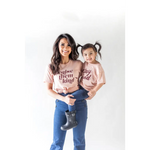 Parent and child in matching pink organic cotton graphic t-shirts against a plain backdrop