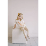 Child in palm tree outfit on a cube, showcasing Shine Bright Star Flexible Lightweight Leggings